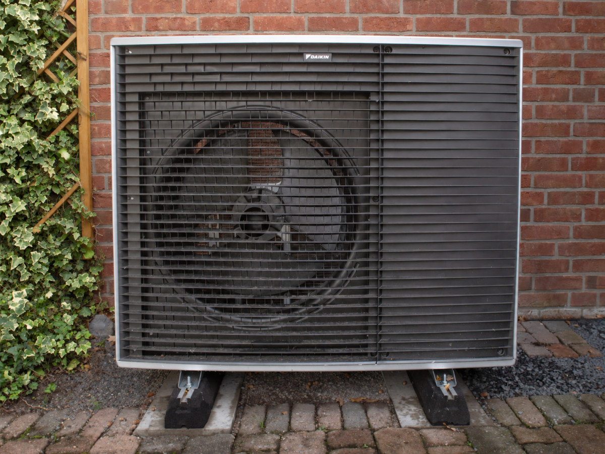 Daikin-Außeneinheit einer Wärmepumpe auf Fundamentsockeln vor einer Klinkerwand